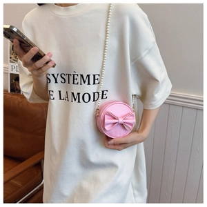 Détail du mini sac rond rose avec un joli nœud et une élégante chaîne en perles blanches
