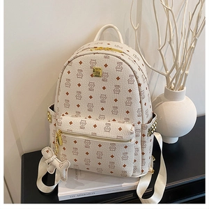 Détail d'un sac à dos crème avec imprimé chat monogramme et fermeture éclair dorée