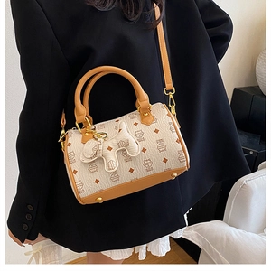 Detail of cream patterned shoulder bag with brown leather trim and cute puppy charm