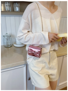 Detail of pink metallic mini crossbody bag with bow and golden chain strap for girls