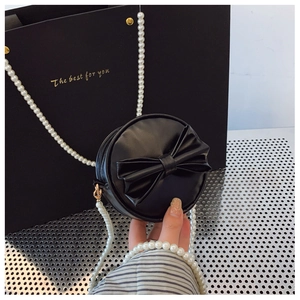 Détail du mini sac rond noir avec grand nœud et élégante bandoulière en perles