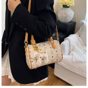 Detail view of the cream Boston bag featuring cartoon cat prints and a cute dog charm