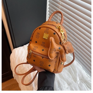 Detail of a brown leather backpack featuring a cat print and dog-shaped bag charm