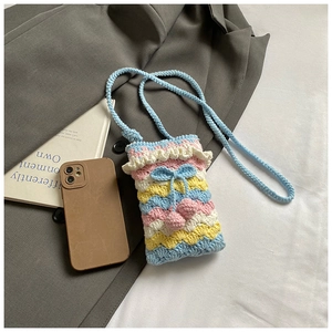 Detail of handmade crochet crossbody bag with colorful wavy patterns and blue bow charm