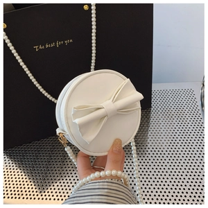 Détail du mini sac rond blanc avec nœud décoratif et bandoulière en perles chics