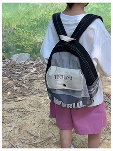 Detail eines farblich abgesetzten Kinderrucksacks mit Logo-Schriftzug im Freien