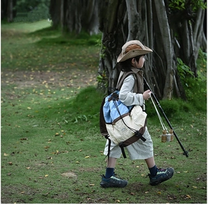 Kids adventure backpack shown in a forest setting with outdoor hiking gear and outfit