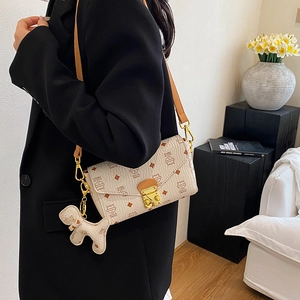 Sac bandoulière crème avec motif chat et fermoir doré porté par un mannequin