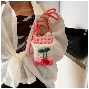 Detail showing hand-knitted rainbow wave pattern bag with 3D cherry charm