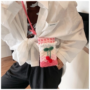 Detail of handmade crochet shoulder bag with 3D cherry pendant and ruffled edge