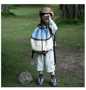 Outdoor scene of a kids drawstring backpack with mountain logo and adventure accessories