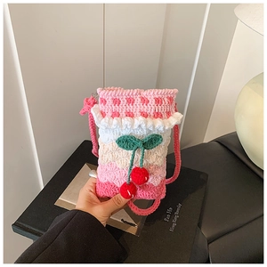 Detail of handmade crochet shoulder bag with pink gradient yarn and cherry charms