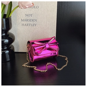 Detail of rose red patent leather mini crossbody bag with metallic bow and gold chain