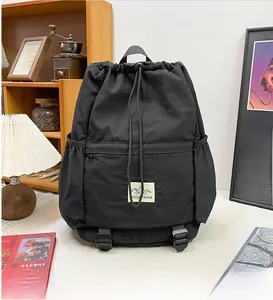 Detailed macro view of black nylon backpack with drawstring closure and mountain patch logo