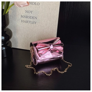 Detail of pink patent leather mini bag featuring a large bow and gold metal chain