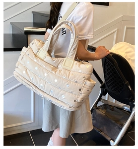 Quilted beige diaper bag with metallic polka dots shown with baby stroller
