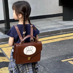 Detail of a brown PU leather kids backpack with cute rabbit pattern and metal clasp