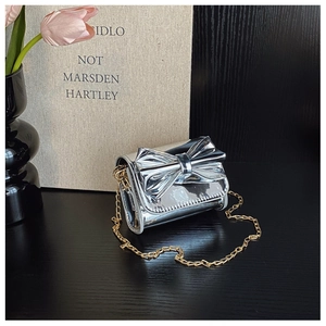 Detailed close-up of metallic silver mini bag with large bow and gold chain strap
