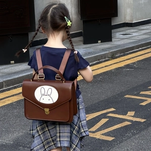 Detail view of a vintage brown leather children's backpack with an adorable rabbit motif