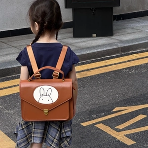 Detailed back view of a toddler wearing a brown rabbit leather backpack on a street