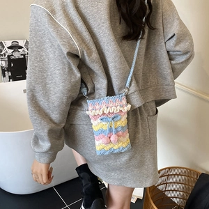 Handmade rainbow knit crossbody bag with cherry charm and bow detail worn by model