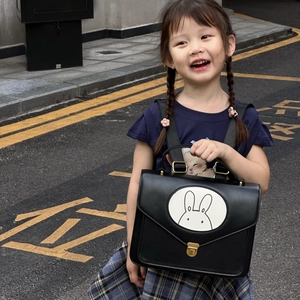Detailed view of child wearing a black leather Miffy backpack on an outdoor street