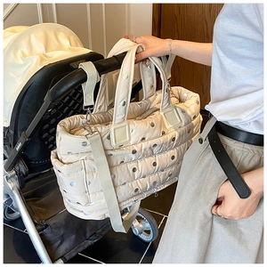 Close-up of beige quilted polka dot mommy bag hanging on a stroller handle