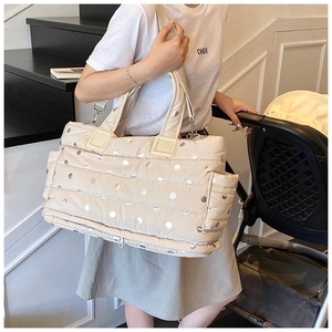 Close-up of beige quilted tote bag with silver polka dots and side pocket on shoulder