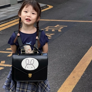 Close-up of black leather kids backpack with cute rabbit illustration and metal buckle
