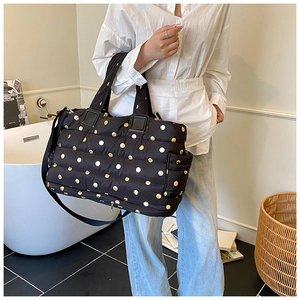 Detailed shot of black quilted tote bag with gold polka dots and expandable zipper base