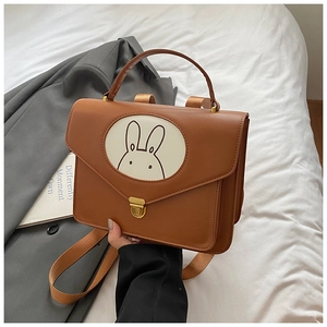 Detail view of a vintage brown leather kids backpack with cute rabbit pattern and metal clasp
