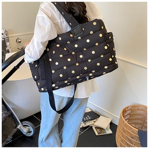 Detail showing the large capacity black quilted tote with golden polka dots on the back