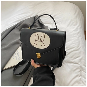 Detail of a black leather children backpack with a minimalist bunny patch and gold buckle