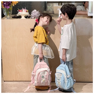 Cute cartoon kids backpacks with star charms shown on models in a cozy room setting