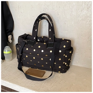 Detailed view of quilted black tote bag with gold polka dots and a baby bottle inside