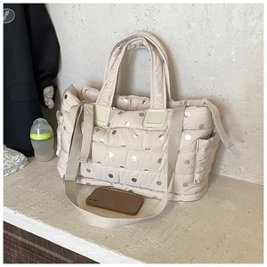 Detailed view of the quilted diaper bag interior with a baby bottle and essentials