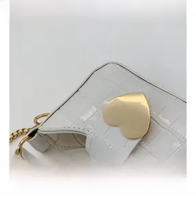 Detail shot of white faux leather bag featuring crocodile texture and heart-shaped metal lock