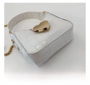 Detail of stone pattern texture and gold heart clasp on kids white crossbody bag