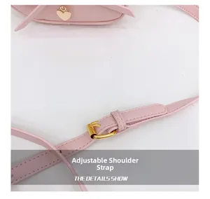 Close-up of pink leather bag featuring an adjustable shoulder strap with gold buckle