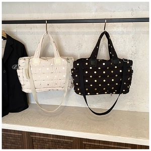 Detailed view of quilted nylon tote bags with polka dots in beige and black finishes