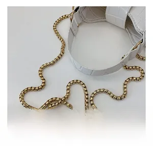 Detailed macro view of white crocodile pattern bag with thick gold metal chain strap