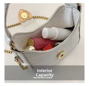 Detail of white crocodile texture bag with heart clasp and interior storage capacity