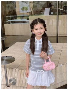 Detail of a pink mini handbag with bow decoration paired with a girl polo shirt and skirt