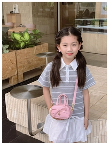 Detail of pink mini bag with bow decoration and heart charm on a young girl model