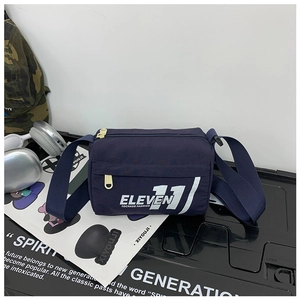 Dettaglio borsa a tracolla bimbo blu navy con scritte bianche su sfondo industriale