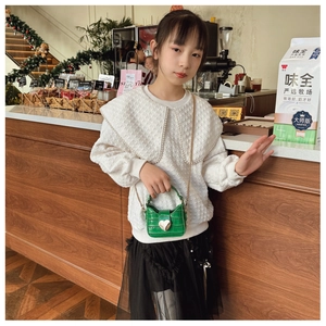Detail of green stone-patterned mini child bag with heart buckle and gold chain strap
