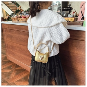 Detailed view of child wearing golden heart crossbody bag with crocodile texture and chain