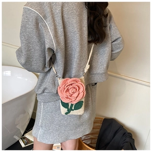 Détail d'un sac bandoulière en tricot avec une rose 3D rose sur tissu crème