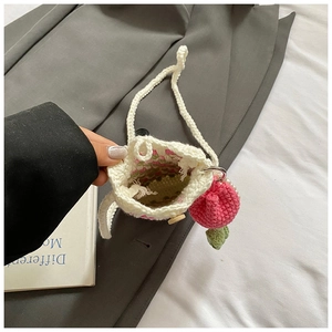 Detail of hand-crocheted shoulder bag with pink strawberry pendant and floral lining