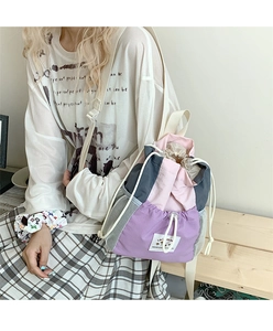 Dettaglio dello zaino con coulisse rosa e viola con tasca laterale in rete e logo di testo